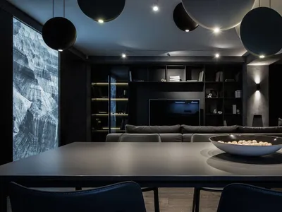 A modern living room with dark concrete flooring, minimalist furniture, and industrial-style lighting fixtures.
