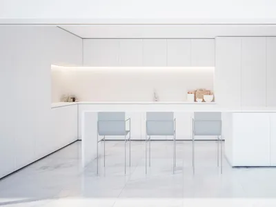 A minimalist white marble kitchen interior with sleek, modern cabinets and a long island.