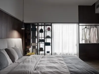 A modern bedroom featuring a bed with a neutral-colored bedspread and pillows, alongside shelves and dressers adorned with ba