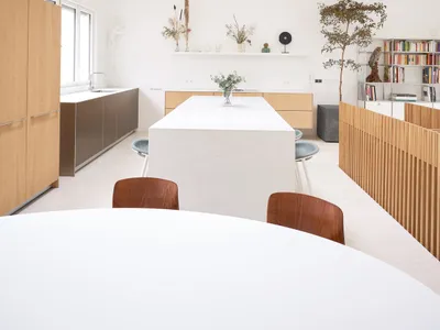 A modern, minimalist kitchen with white marble countertops and a large white marble island.