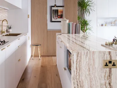 Modern kitchen with marble countertop and wooden walls.
