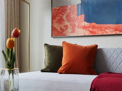 Contemporary living room with a plush gray couch adorned with vibrant orange and green throw pillows and a burgundy throw bla