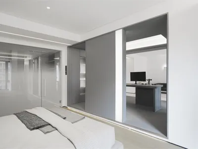 Modern bedroom featuring glass, wood, and leather furniture, showcasing contemporary design elements and sleek finishes.
