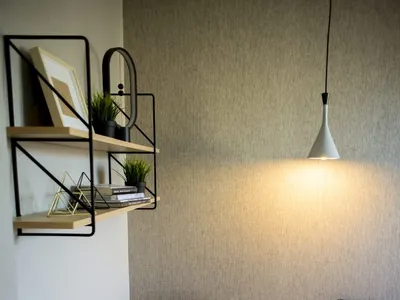 A minimalist bedroom with a bed, chair, shelves, and a hanging lamp.