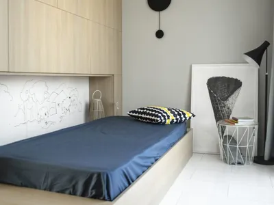 Minimalist bedroom with a wooden platform bed, navy sheets, and a monochrome abstract painting