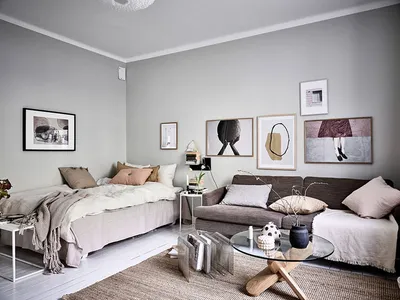 A minimalist living room with light-colored furniture, cushions, and throw blankets.