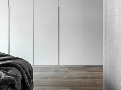 Minimalist bedroom with metallic cabinets, gray blanket, and gray walls.