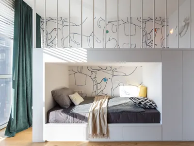 A modern bunkbed space with white walls and wooden floor, featuring a comfortable bed with grey and black bedding and a wall-