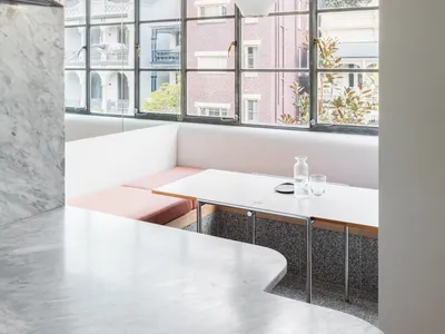 A photograph of a modern restaurant with a glass wall and a seating area.