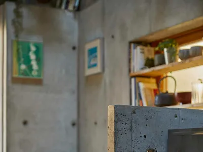 A close-up of a modern industrial living room with a prominent concrete fireplace and wooden seating.