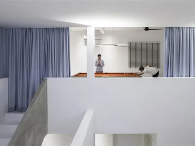 Minimalist living room with concrete walls and floor, featuring a white ceiling and blue curtains.