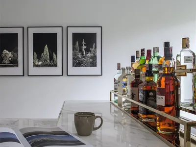 A sleek, modern bar featuring a marble countertop with a variety of alcoholic beverages and an open book.