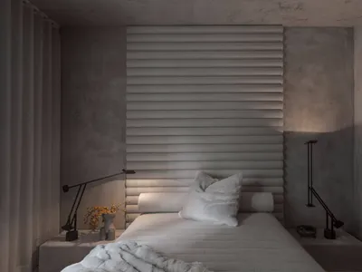 Modern minimalist bedroom featuring a fabric headboard and soft lighting.