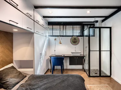 Modern minimalist bedroom with black, white, and gray color scheme, featuring a wooden bed, white floating cabinets, and a sm