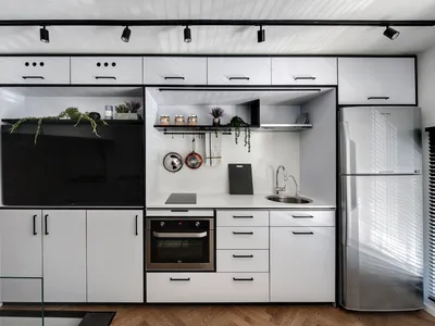 Modern minimalist kitchen with white laminate cabinets, stainless steel appliances, and black countertops.
