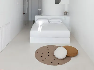 Minimalist bedroom with white bed, round light fixture, and fabric accents.