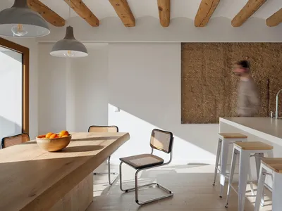 A modern kitchen featuring a wooden dining table with a bowl of oranges on it.