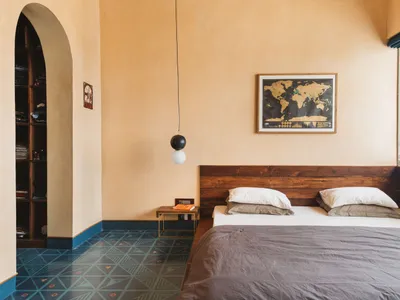 A minimalist bedroom featuring wooden furniture, a concrete floor with geometric patterns, and a world map on the wall.