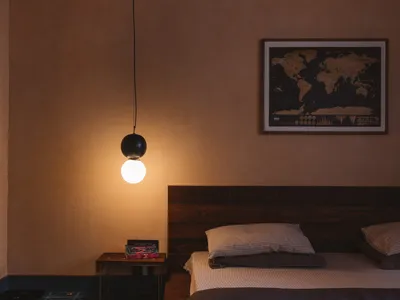A minimalist bedroom featuring wooden furniture and a hanging light fixture.