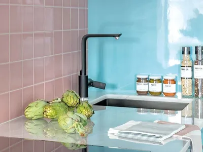 A minimalist kitchen with a glass countertop, pink tiles, and blue backsplash.