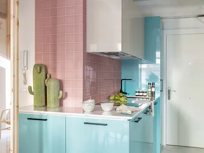 A modern kitchen with light blue cabinets and pink tiled walls.