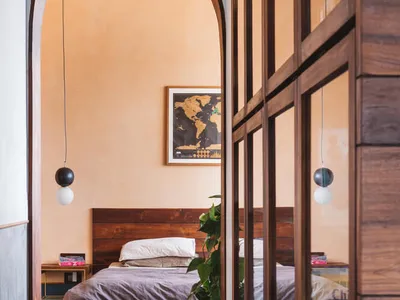 A minimalist bedroom with wooden furniture, concrete floor, and a green plant.