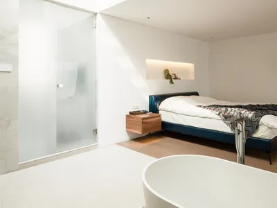 Modern minimalist bedroom featuring a concrete floor and large glass window.