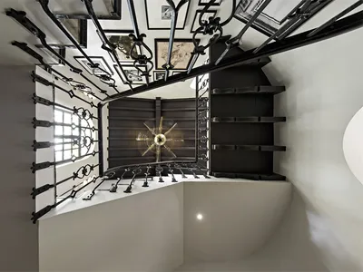 A black metal staircase with intricate railings leading to a white interior space.