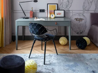 A modern home office with a grey desk, black chair, and a wall decorated with intricate grey owl sketches.