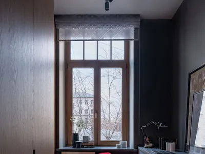 Modern home office with a red chair, window seat, and dark wood flooring.