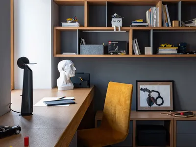 A modern home office with a wooden desk and shelves.