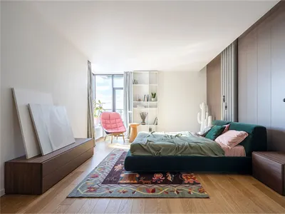 Minimalist bedroom with wooden furniture, carpet flooring, and fabric bedding.