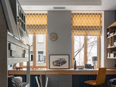 Minimalist home office with a wooden desk, yellow geometric window shades, and a grey and white striped rug.