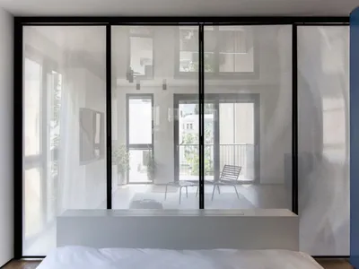 A modern bedroom featuring a large glass wall that provides a view of the outside and allows natural light to flood the space