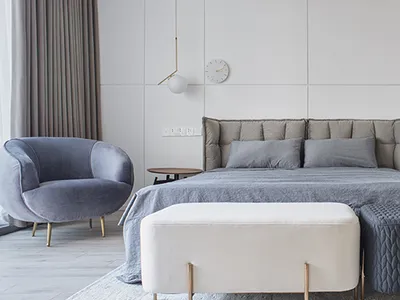Modern minimalist bedroom with white walls, grey upholstered bed, and light grey curtains.
