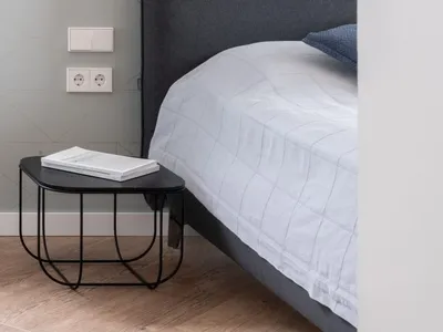Modern minimalist bedroom with a fabric bed, glass pendant light, and wooden floor.