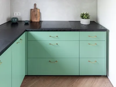 A minimalist kitchen with green cabinets and concrete countertops.