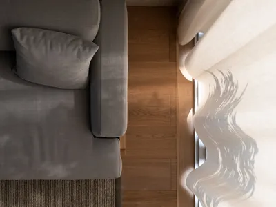 Gray sofa with a single cushion and a window with sheer curtains letting in sunlight, viewed from above.