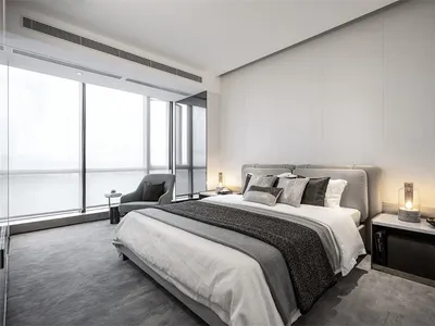 Modern and stylish bedroom with gray bedding and a comfortable seating area in front of large windows.