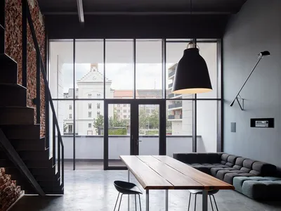 A spacious industrial living room with concrete and wooden furniture.