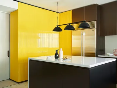 Modern kitchen featuring a yellow backsplash and stainless steel appliances, surrounded by brown cabinets.