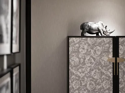 Modern bedroom interior with floral pattern walls and silver rhinoceros statue on cabinet.