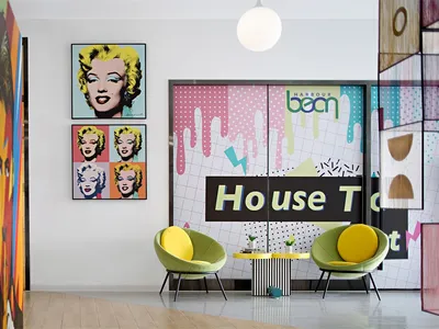 A modern restaurant interior featuring colorful geometric patterns and vibrant yellow chairs.