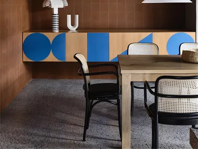 A modern restaurant interior featuring wooden tables and geometric-patterned walls.