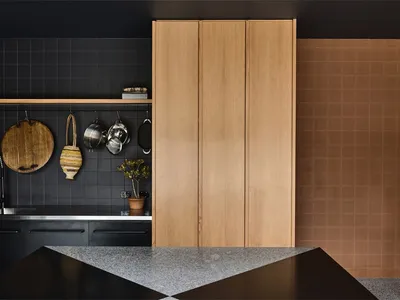 Modern kitchen with wooden cabinets, black backsplash, and a stone countertop.