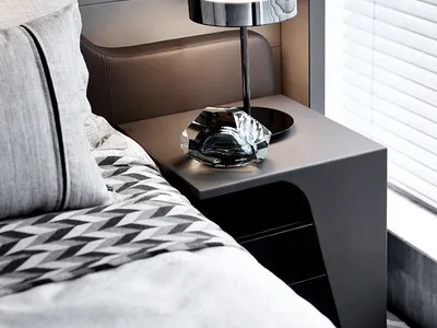 A minimalistic bedroom featuring a metallic table lamp on a sleek, modern nightstand.