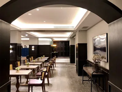 A spacious, modern restaurant interior with wooden tables and chairs, archways, and a warm, inviting atmosphere.
