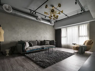 Modern industrial living room with concrete walls, grey sofa, and black coffee table on a grey rug.