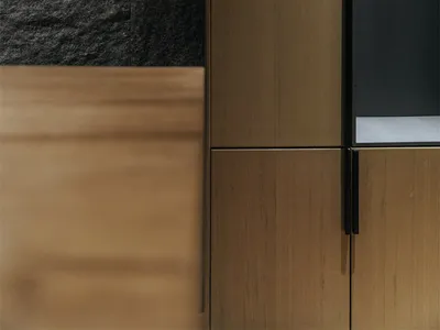 A minimalist residential kitchen featuring wooden cabinets and a stone wall.