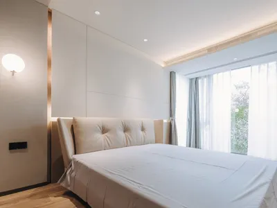 Modern bedroom with a white bed frame and white curtains.